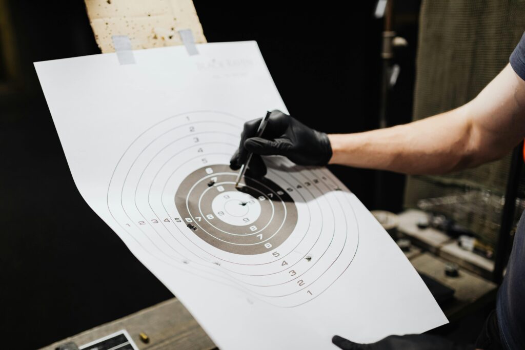 Close-up of a person marking hits on a shooting range target with a marker.